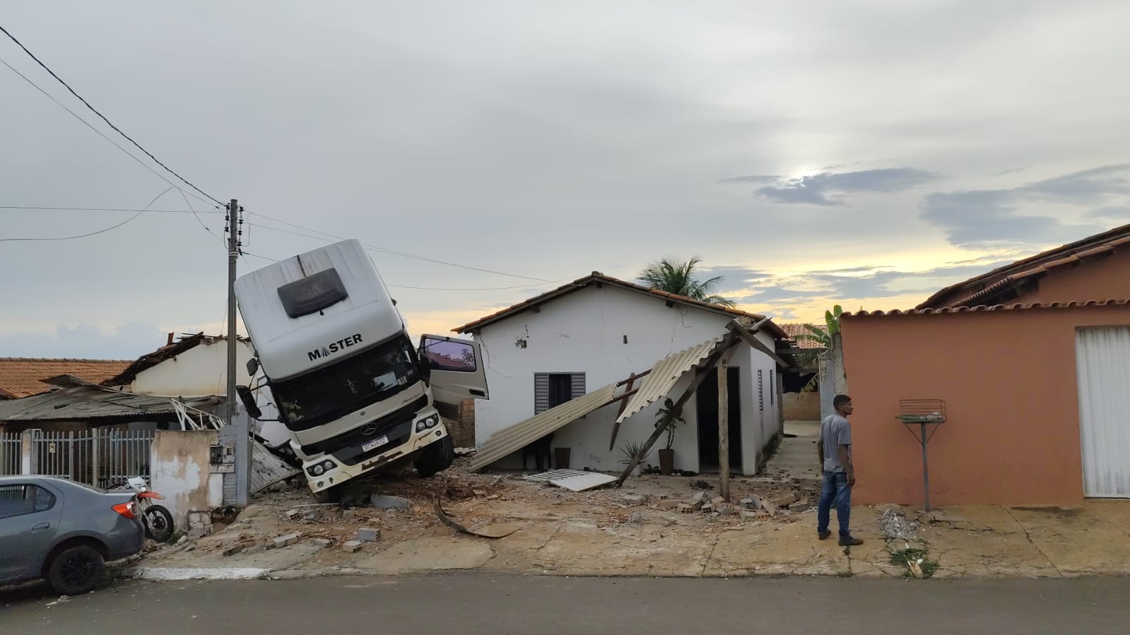 Caminhão desgovernado atinge moto, carro e para em residência