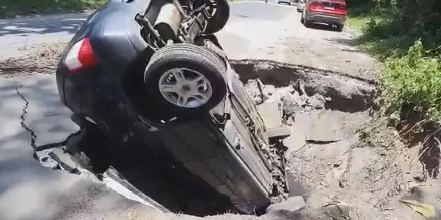 Cratera se abre no meio da rua e ‘engole carro’