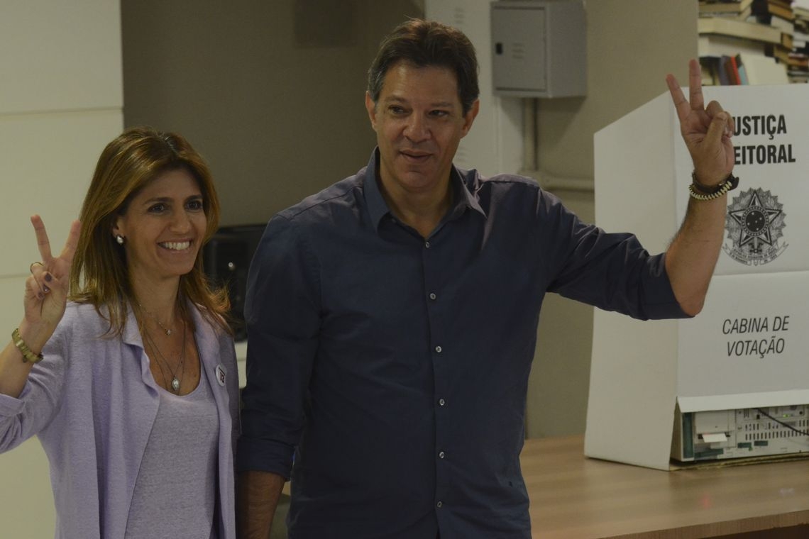 Com camisa azul, Haddad vota e faz sinal de vitória